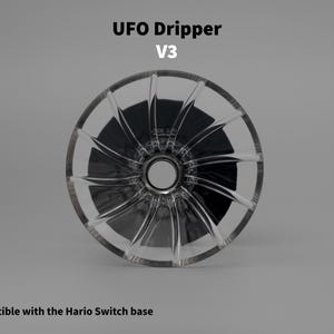 Könnte beinhalten: Ein klarer, kreisförmiger UFO Dripper V3 mit einem zentralen Loch und radialen Rillen. Der Text "UFO Dripper V3" steht oben. Der Text "Compatible with the Hario Switch base" steht unten.