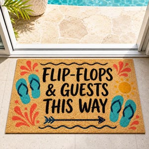 以下が含まれることがあります： 「FLIP-FLOPS & GUESTS THIS WAY」の黒い文字が入った長方形のコイアマット。青いビーチサンダル、黄色の太陽、赤とオレンジの装飾が施されています。背景は明るい茶色です。