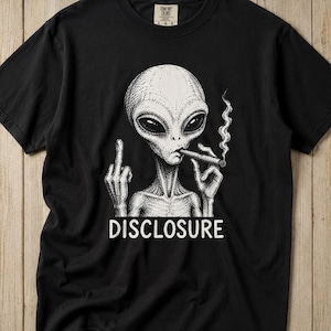 May include: A black short-sleeve t-shirt featuring a white graphic illustration of an alien smoking a cigar while giving the middle finger. The word DISCLOSURE is printed in white capital letters underneath the alien figure on the front of the shirt.