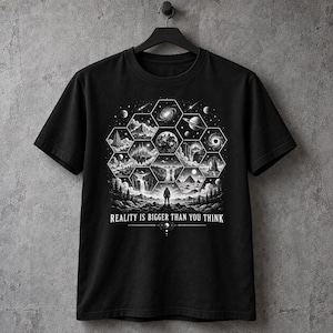 May include: A black t-shirt featuring a white graphic print of a central figure standing before a landscape of hexagonal panels containing various celestial and terrestrial scenes, with the text "REALITY IS BIGGER THAN YOU THINK" printed below.