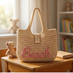 Peut inclure: Un sac fourre-tout en crochet beige avec le mot "Beach" en script rose. Le sac a une forme rectangulaire avec une fermeture à bouton et deux poignées. Le sac est posé sur une table en bois à côté d'un petit ours en peluche.