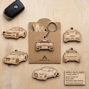 Peut inclure: Porte-clés en bois représentant des modèles de voitures, dont une Porsche et une BMW. Les porte-clés sont découpés au laser avec des contours de voitures détaillés. Un porte-clés de voiture noir et une carte avec "APEX OUTLINES" et "Classic 911" sont également présents.