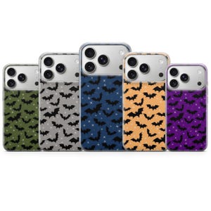 Op de afbeelding: Vijf smartphonehoesjes op een rij, elk met een herhalend patroon van zwarte vleermuizen en kleine witte sterren. De achtergrondkleuren van de hoesjes zijn olijfgroen, lichtgrijs, donkerblauw, oranje en paars, allemaal met camera-uitsparingen.