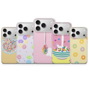 May include: A collection of five phone cases with colorful cereal-themed designs. The cases feature images of cereal bowls, cereal pieces, and a spoon filled with cereal. The cases are in various colors, including pink, yellow, and white.