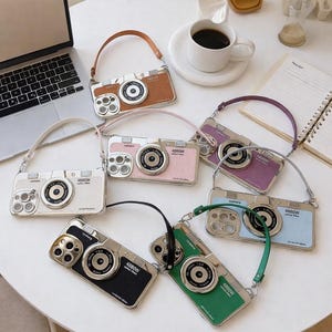 May include: A collection of camera-shaped phone cases in various colors, including brown, pink, white, purple, blue, green, and black. Each case has a silver-colored lens and strap, and the text "4880W" is visible.