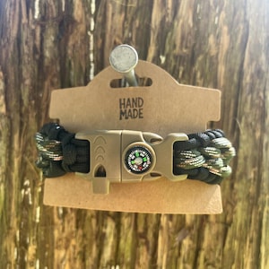 May include: A handmade paracord bracelet with a compass and a tan clasp. The bracelet is black and green camouflage. The tag reads "HAND MADE".