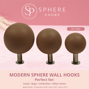 May include: Three sand-coloured sphere wall hooks with a matte finish. The hooks have a metal base and are available in three sizes: 6cm (2.36"), 5cm (1.97"), and 4cm (1.67"). The image text says "MODERN SPHERE WALL HOOKS".