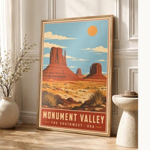 Può includere: Una stampa artistica rettangolare incorniciata con un'illustrazione stilizzata della Monument Valley con formazioni rocciose rosse, un paesaggio desertico e un sole arancione brillante in un cielo blu. Il testo recita MONUMENT VALLEY THE SOUTHWEST USA.