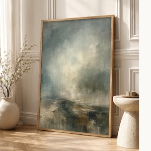 Peut inclure: Une œuvre d'art murale rectangulaire verticale représentant une peinture de paysage abstrait dans un cadre en bois clair. L'œuvre affiche un ciel atmosphérique et sombre dans des tons de bleu, gris et crème, vers un premier plan texturé.