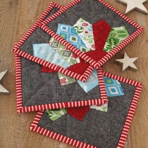 May include: Set of four quilted fabric pot holders with a red, white and blue patchwork design. The pot holders have a red and white striped border.