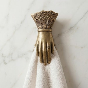 May include: A white ceramic mug with a black handle and the text "But First, Coffee" in a black, handwritten-style font. The mug is on a white surface.