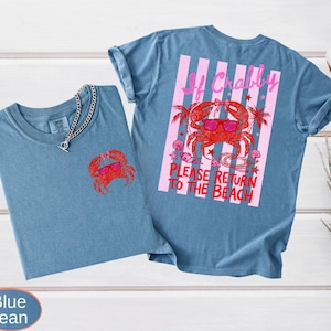 May include: Two blue jean t-shirts. One shirt has a red crab graphic on the front. The other shirt has a larger crab graphic on the back with the text "If Crabby, Please Return to the Beach" in pink and red.