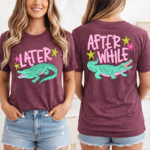 May include: Maroon t-shirts with a graphic of a green alligator and the text "LATER" on the front and "AFTER WHILE" on the back. The text and alligator are outlined in pink and green with yellow star accents.