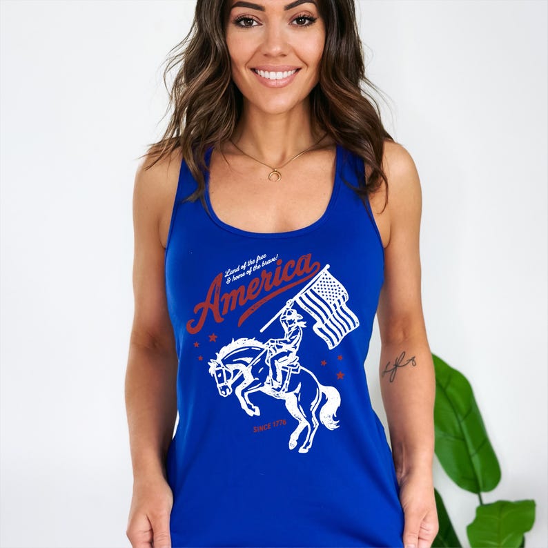 May include: Royal blue tank top with a patriotic design. The graphic features the word "America" in red script, a rider on a horse holding an American flag, and the text "Since 1776."