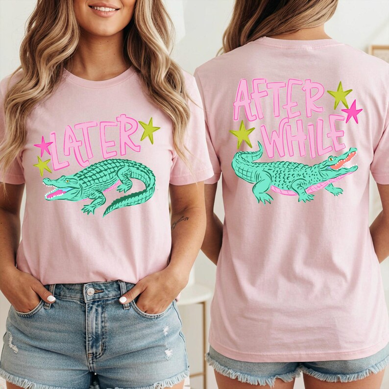 May include: Pink t-shirts with a teal alligator graphic and text. The front of the shirt says "LATER" with a star, and the back says "AFTER WHILE" with a star. The shirts are worn by a person.