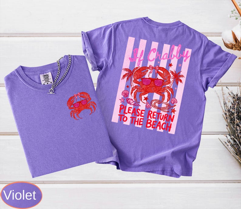 May include: Two violet t-shirts with a crab graphic. One shirt has a small crab on the front, the other has a larger crab design on the back with text that reads "If Crabby, Please Return to the Beach."