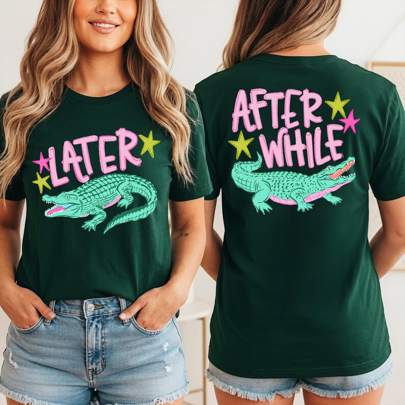 May include: Dark green t-shirts with a graphic of a teal alligator and the text "LATER" on the front and "AFTER WHILE" on the back. The text and alligator are outlined in pink and yellow. The model is wearing blue jean shorts.