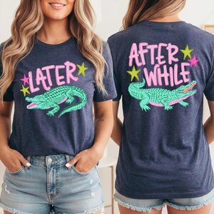 May include: Navy blue t-shirt with a teal alligator graphic and the text "LATER" on the front. The back of the shirt features the text "AFTER WHILE" and a matching alligator design. Pink and yellow accents complete the design.