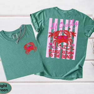 May include: Two light green t-shirts. One shirt has a small red crab graphic on the front. The other shirt has a larger crab graphic with sunglasses and the text "If Crabby Please Return to the Beach" on the back.