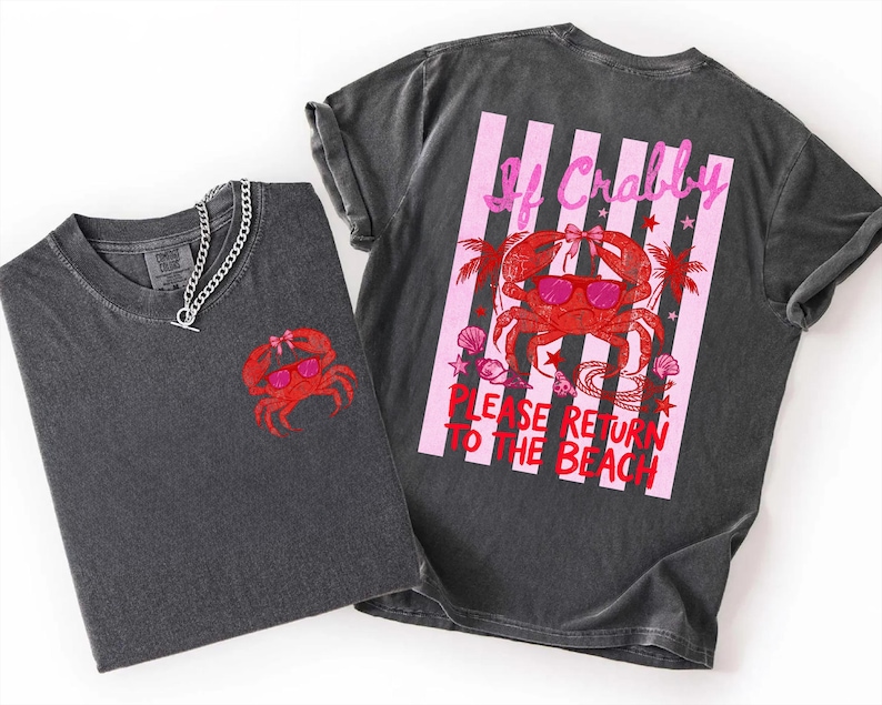 May include: Two dark gray t-shirts with a red crab graphic wearing sunglasses. One shirt has the crab on the front, the other has a crab graphic with text that reads "If Crabby, Please Return to the Beach" on the back. A silver chain necklace is on one shirt.