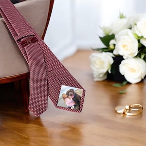 May include: A red patterned tie with a small square photo of a woman and a dog on the front.