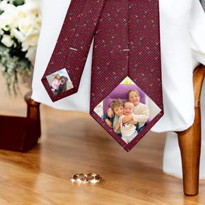 May include: A red patterned tie with two photo inserts. The top insert shows a woman and a dog. The bottom insert shows three children.