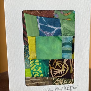 May include: A framed patchwork quilt with green, brown, and yellow fabric squares. The quilt is signed "Carolyn Bead Whitlow".