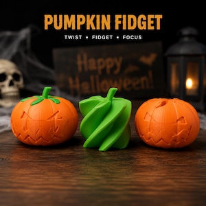 May include: Two orange pumpkin-shaped fidget toys with carved jack-o'-lantern faces and one green spiral-shaped fidget toy. The text PUMPKIN FIDGET TWIST • FIDGET • FOCUS is displayed above the objects. The items are arranged on a dark surface.