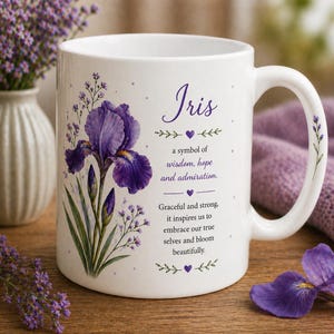May include: White ceramic mug featuring a purple iris flower illustration and the word "Iris". The mug includes text about the iris flower's symbolism of wisdom, hope, and admiration. A handle is on the right side of the mug.