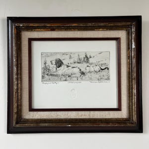 May include: Framed black and white print of two dogs in a landscape. The print is in a dark brown wooden frame with a linen mat. The print is signed and titled "Choppy and Spotty".