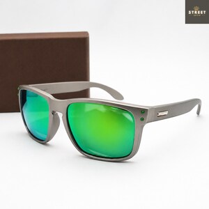 May include: Gray sunglasses with green mirrored lenses. The sunglasses have a rectangular frame with a matte finish and a small metal accent on the temples. The lenses reflect a bright green color. The brand name "STREET OPTIK" is in the top right corner.