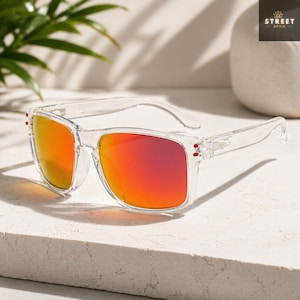 May include: Clear-framed sunglasses with vibrant orange-red lenses. The sunglasses have a square shape and small red accents on the frame. The lenses reflect light, and the sunglasses are displayed on a white surface.