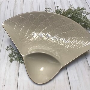 Può includere: Un piatto da portata in ceramica bianca con un design a festoni e un bordo dorato. Il piatto ha una sezione divisa per servire più articoli.