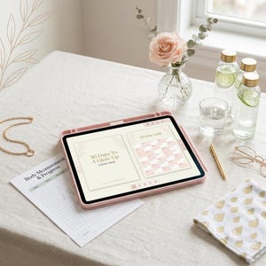 Peut inclure: Une tablette dans un étui rose affichant un planificateur numérique intitulé 30 Days To A Glow-Up et une grille de 30 jours. À côté se trouvent une feuille de suivi Body Measurement & Progress, un stylo doré, une chaîne dorée, des lunettes et deux bouteilles d'eau avec des tranches de concombre.