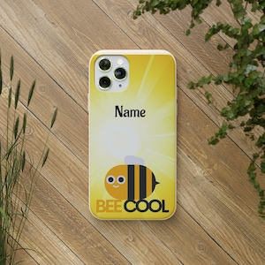 Könnte beinhalten: Eine gelbe Smartphone-Hülle mit einer Grafik einer Comic-Biene mit schwarzen Streifen und großen Augen. Das Design umfasst einen sonnenstrahlenartigen Hintergrund, das Wort Name in schwarzer Schrift und den Text BEE COOL in fetten schwarzen Buchstaben.