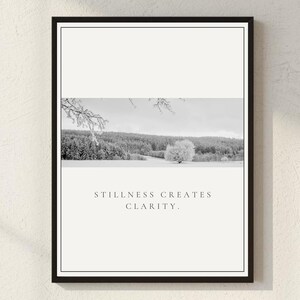 May include: Framed black and white print featuring a winter landscape with snow-covered trees and a single tree in the center. The print includes the text "STILLNESS CREATES CLARITY" in a minimalist design, suitable for home decor.