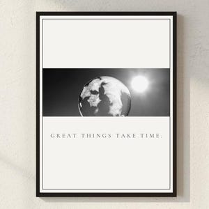 Puede incluir: Impresión enmarcada en negro con una imagen en blanco y negro de un globo terráqueo y el sol. El texto "GREAT THINGS TAKE TIME" está impreso en una fuente minimalista en la parte inferior. Fondo blanco.