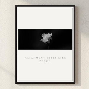 May include: A framed monochrome art print. The image shows a white flower set against a black backdrop, with the words "ALIGNMENT FEELS LIKE PEACE". The frame is black, creating a minimalist aesthetic.