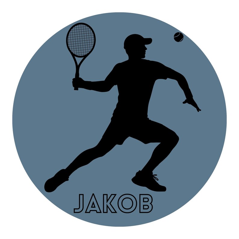 May include: A circular graphic featuring a black silhouette of a tennis player in a cap holding a racket, with a tennis ball in the air. The background is a solid slate blue colour. The name JAKOB is printed in white capital letters at the bottom.