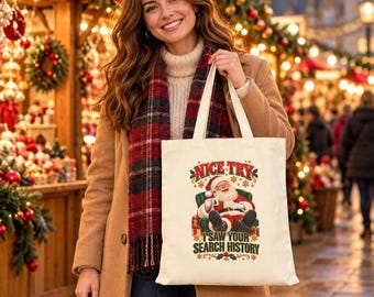 May include: A cream-colored canvas tote bag featuring a graphic of Santa Claus sitting in a green armchair. The text above reads NICE TRY and the text below reads I SAW YOUR SEARCH HISTORY, decorated with red and green festive accents.