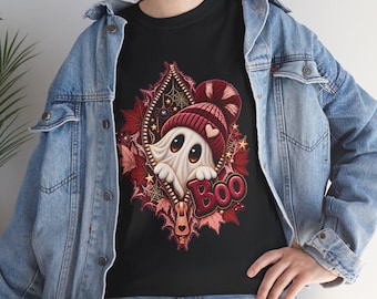 May include: A black t-shirt featuring a graphic of a white ghost wearing a red knit beanie with a pom-pom, peeking out from a vertical zipper opening surrounded by red autumn leaves, spiderwebs, and the word Boo in red lettering.