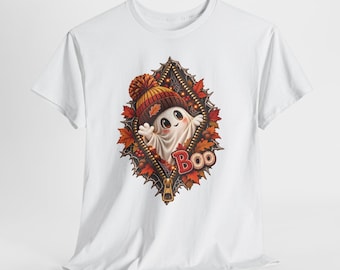 May include: A white t-shirt featuring a graphic of a ghost wearing a knit hat, emerging from a zipper opening surrounded by autumn leaves and acorns. The word Boo is printed in red and orange letters at the bottom of the zipper design.