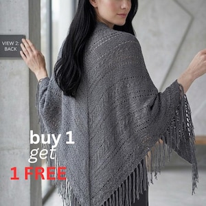 Puede incluir: Un chal gris tejido con flecos. El chal lo lleva una persona. Presenta un patrón geométrico y flecos en el borde inferior. El texto "buy 1 get 1 FREE" está en la imagen.