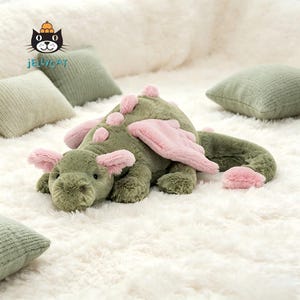 Könnte beinhalten: Eine weiße Keramik-Tasse mit schwarzem Henkel und dem Text "But First, Coffee" in fetter, schwarzer Schrift. Die Tasse steht vor einem verschwommenen Hintergrund, der eine gemütliche Umgebung suggeriert.