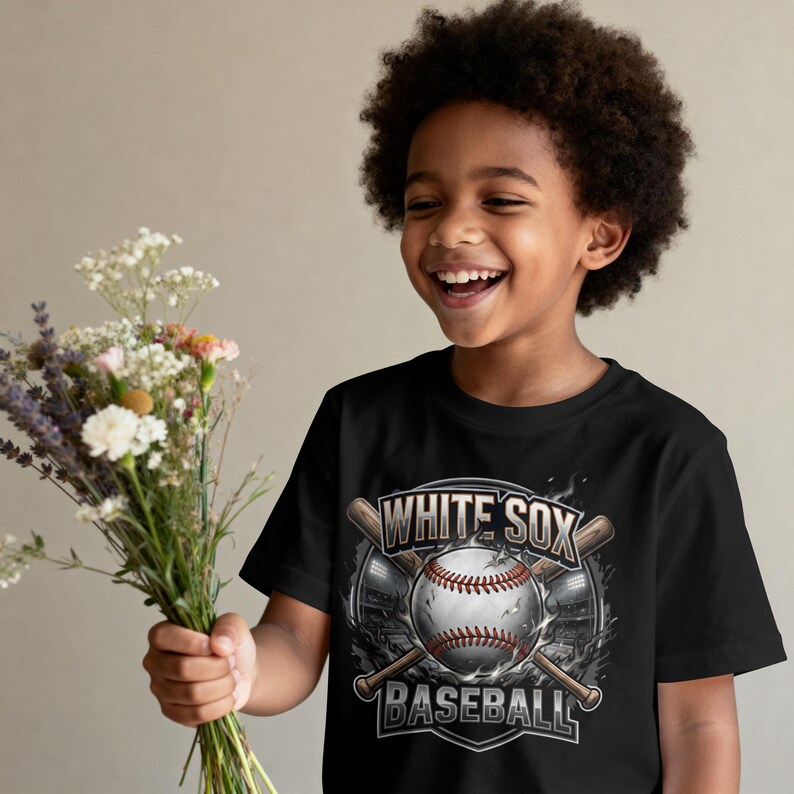 Op de afbeelding: Zwart T-shirt met een honkbalontwerp. De tekst luidt "WHITE SOX BASEBALL" boven en onder een honkbal- en gekruiste knuppelafbeelding. Het T-shirt wordt gedragen door een lachend kind.