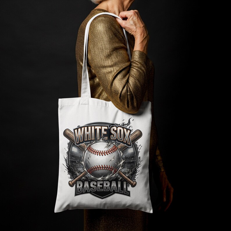 Op de afbeelding: Witte draagtas met een honkbalontwerp. Het ontwerp bevat een honkbal met rode stiksels, gekruiste knuppels en de tekst "WHITE SOX BASEBALL". De tas wordt vastgehouden door een persoon die een goudkleurige top draagt.