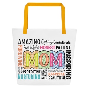 May include: White tote bag with yellow handles. The bag features the word "MOM" in colorful letters, surrounded by words like "Amazing," "Caring," and "Inspiring." A perfect gift for Mother's Day.