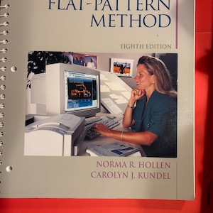 May include: A spiral-bound textbook titled Pattern Making by the Flat-Pattern Method, Eighth Edition, by Norma R. Hollen and Carolyn J. Kundel. The cover features a photograph of a person using a computer to design patterns on a screen.