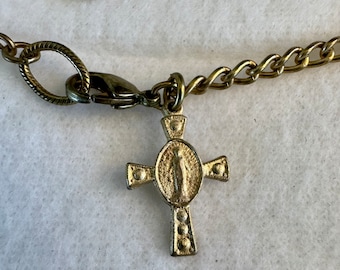 May include: A gold chain necklace with a gold cross pendant featuring a religious figure. The chain has a lobster clasp.