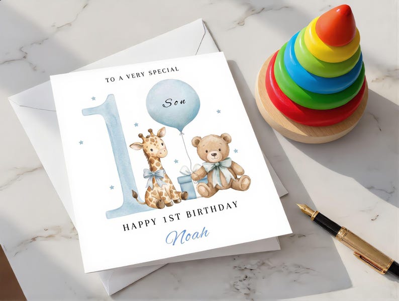 May include: A white greeting card featuring a large light blue number one, a watercolor illustration of a giraffe and a teddy bear with blue bows, a light blue balloon, and the text TO A VERY SPECIAL Son HAPPY 1ST BIRTHDAY Noah.